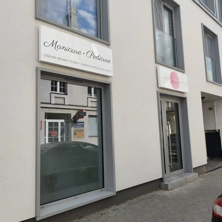 Weisses Firmenschild fuer Manicure Pedicure und kosmetische Dienstleistungen an der Fassade