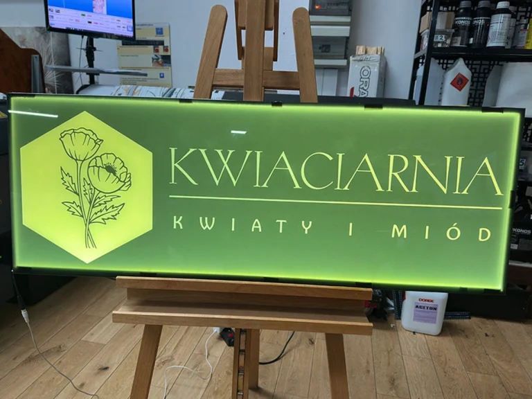 Beleuchtetes Werbeschild fuer Kwiaciarnia mit gruenem Hintergrund
