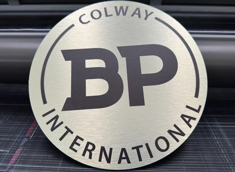 Hochwertiges rundes Werbeschild aus gebuerstetem Gold-Metall mit schwarzem "BP International" Aufdruck