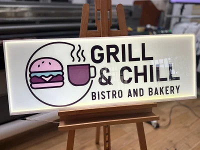 Leuchtendes Werbeschild Grill & Chill Bistro and Bakery mit Burger- und Tassenlogo